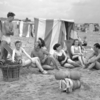 Young people sat around beach huts in 1950