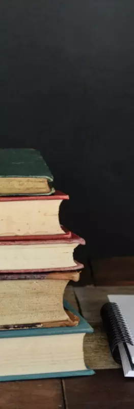 A pile of books next to a notebook